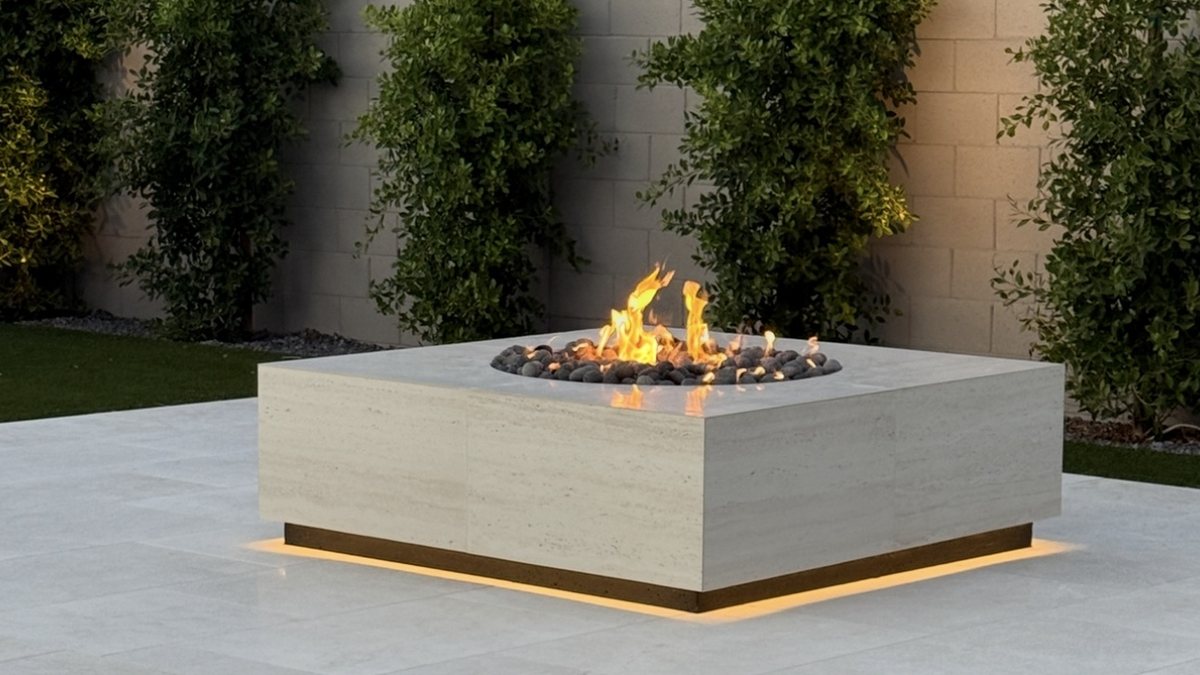 A square fire table burning on a patio at dusk with lighting under the base