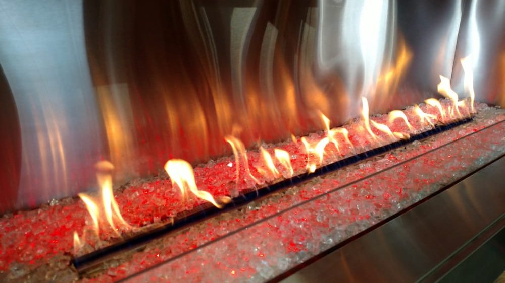 A linear gas fireplace burning over fire glass in the Mesa showroom