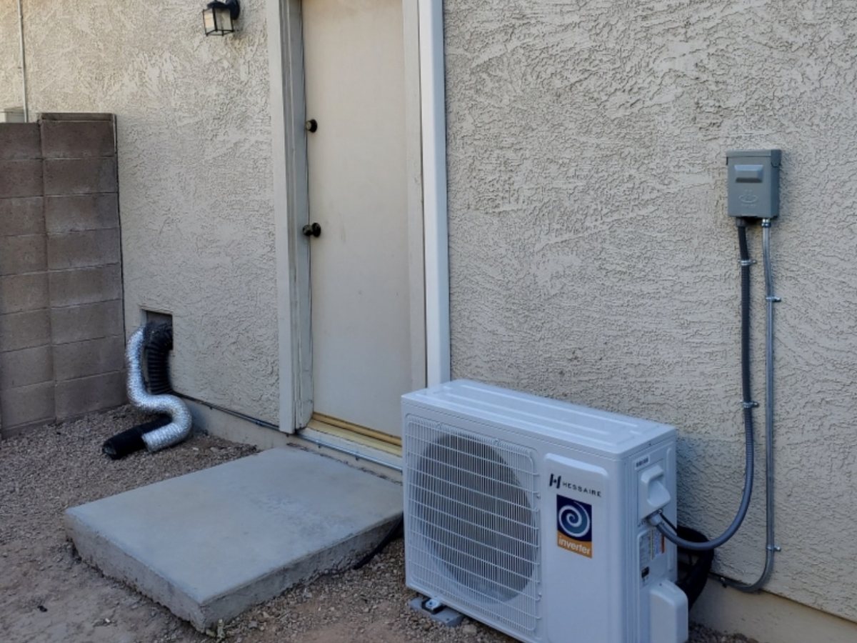 A Hessaire mini split outdoor unit installed on a pad against a stucco wall in Mesa