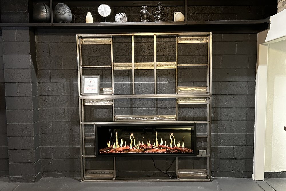 A linear fireplace set into a black brick wall in the showroom