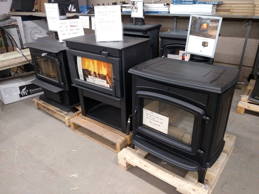 Wood stoves lined up on the showroom floor, one of them lit